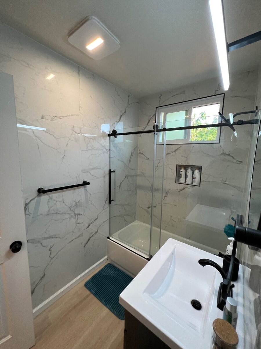 Remodeled bathroom with marble-look tile shower and glass enclosure