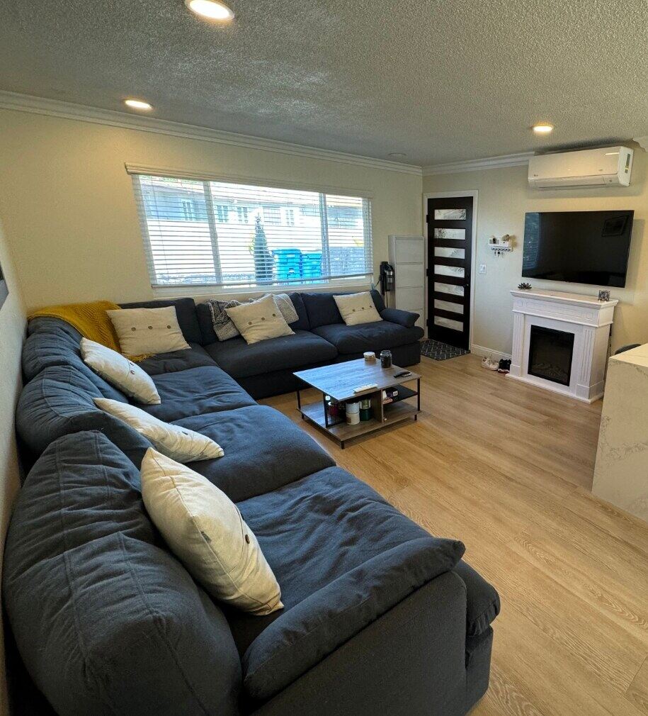 Living room with sectional, mounted TV, and open view to the kitchen