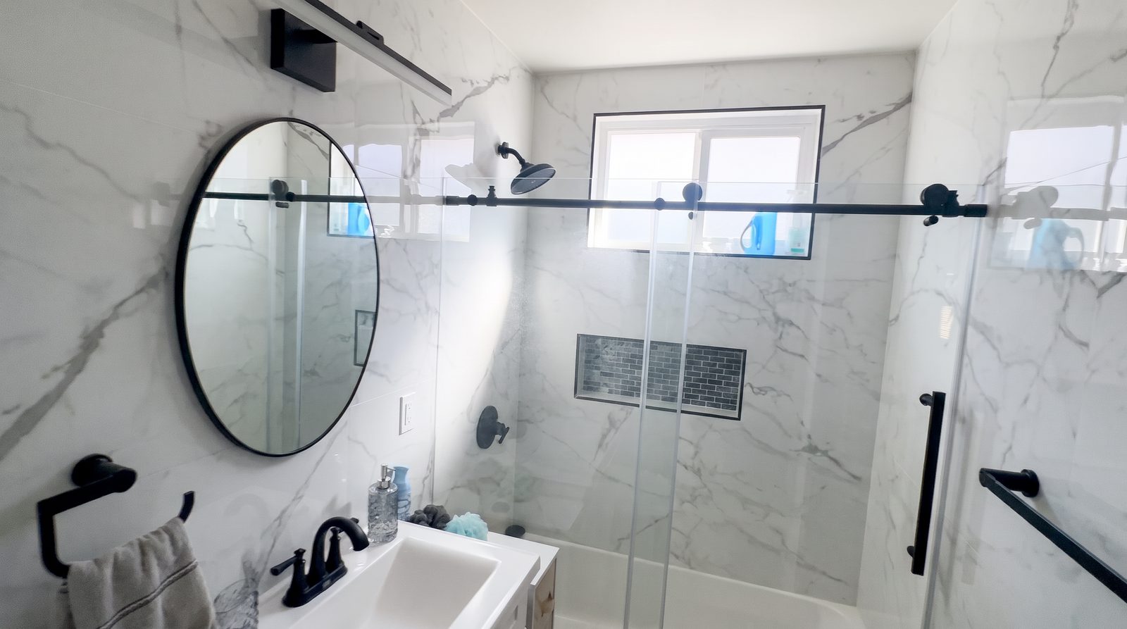 Bathroom with marble tile, walk-in shower and vanity at Her Aria recovery residence serving Los Angeles and San Bernardino Counties