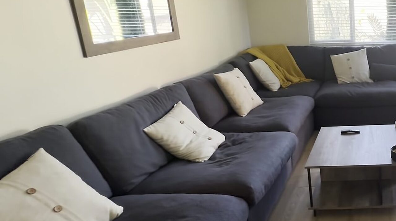 Furnished living room with sectional seating and natural light at Her Aria women's recovery residence serving Los Angeles and San Bernardino Counties